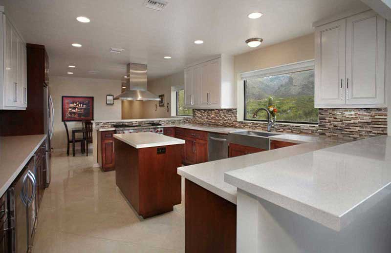 A kitchen with white counters and brown cabinets