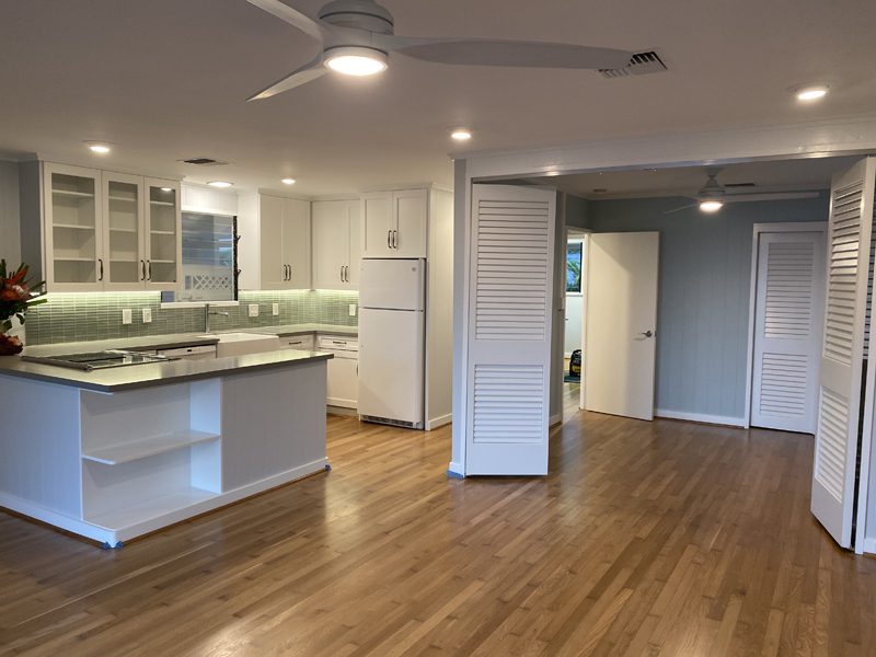 A kitchen with white appliances and wooden floors.